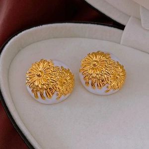 Macro view of vintage gold daisy floral earrings on a white velvet jewelry box