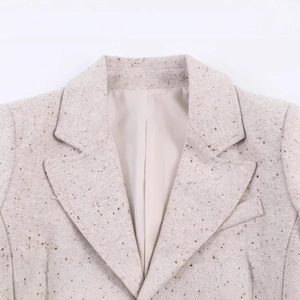 Gros plan d'un blazer en tweed avoine avec revers crantés et tissu tissé texturé