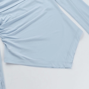 Detailed close-up of light blue top featuring side ruched gathering and hemline stitching