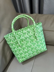 Detail of green checkerboard woven tote bag featuring sawtooth edge and round handles