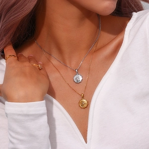 Detail of layered gold and silver starburst pendant necklaces and rings on model