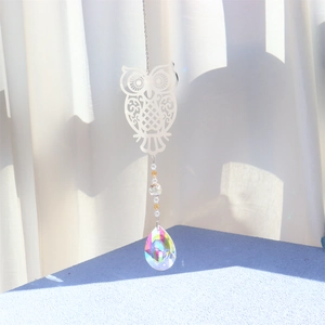 Detailed close-up of a metal owl pendant with yellow beads and clear crystal prism ball