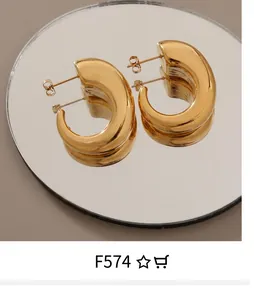 Macro shot of chunky 18K gold plated hoop earrings with mirror finish on magazine background