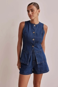 Dettagli del gilet in denim blu scuro con bottoni ambra e pantaloncini a vita alta