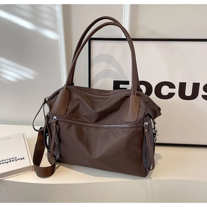 Close-up of a large dark brown nylon tote bag with leather handles and smooth zipper details