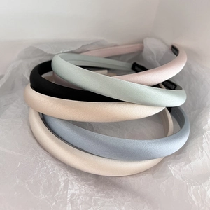 Detailed view of assorted satin headbands in pastel colors on white tissue paper background