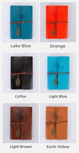 Macro shot of six vintage leather journals with leaf embossing and metallic leaf charms