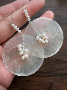 Close-up of silver drop earrings featuring freshwater pearls and clear quartz discs