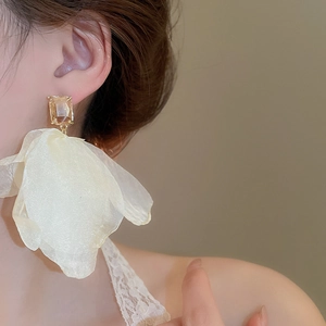 Detailed close-up of a oversized champagne mesh floral earring with a sparkling crystal stud