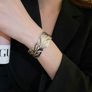 Macro detail of the polished leaf-shaped silver metal bracelet on a model wrist