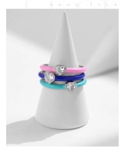 Detailed macro view of S925 silver rings with colorful enamel and heart-cut cubic zirconia