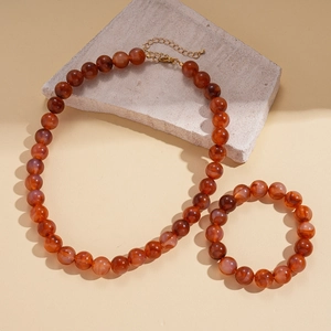 Detailed shot of ethnic acrylic beaded necklace and bracelet set on a stone display