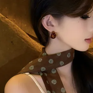 Macro shot of resin drop earrings with gold rim finish worn on model's ear