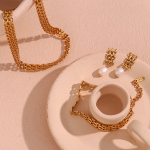 Detail of 18K gold plated jewelry set with necklace, pearl earrings and bracelet
