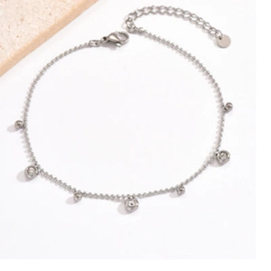 Detail of silver bead anklet with round charms and sparkling cubic zirconia stones