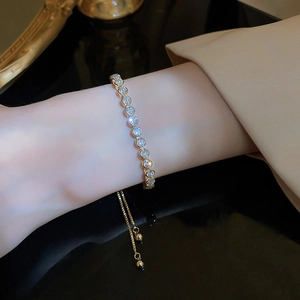 Close-up of a gold adjustable wave bracelet with sparkling diamonds on a wrist
