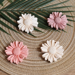 Macro detail of daisy flower silicone resin molds in pink and white on a woven mat