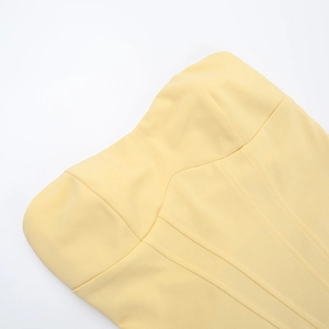 Detailed view of pale yellow strapless dress showing textured fabric and structural seams