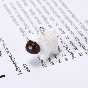 Close-up of a resin sheep charm with curly white texture and a silver metal hanging ring