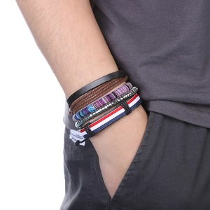 Gros plan de bracelets multicouches en cuir et tressés avec carte de l'Afrique au poignet