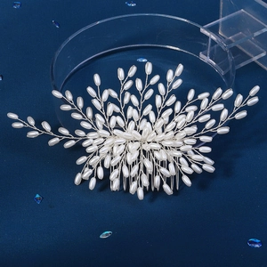 Handmade bridal hair comb with silver flower branches and white pearls on blue surface