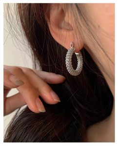 Macro view of silver U-shaped hoop earrings encrusted with rows of sparkling zircon stones