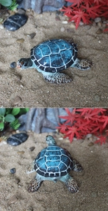 Dettaglio decorazione tartaruga in resina con guscio blu su sabbia finta da spiaggia