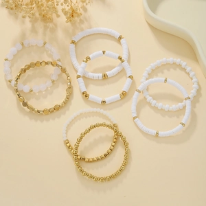 Detail shot of white heishi beads and gold plated charms in a bohemian stacked bracelet set