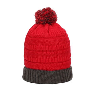 Détail de la maille d'un bonnet d'hiver rouge et gris avec un pompon moelleux soigné