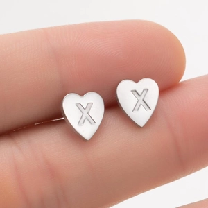 Gros plan d'une puce d'oreille en forme de cœur en acier inoxydable avec la lettre X