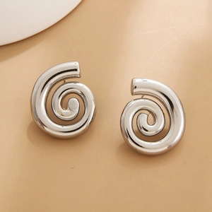 Close-up of silver-tone polished geometric spiral stud earrings in a minimalist style