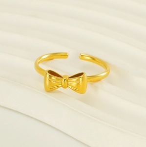 Macro detail of 18K gold-plated bow ring on fabric, showing texture and open band