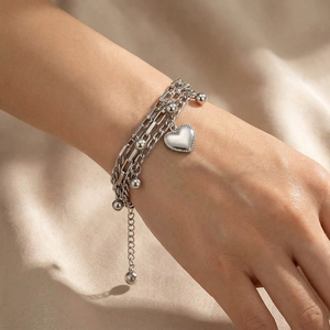 Close-up of multi-layer silver heart bracelet with polished beads on female wrist