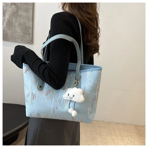Detail of light blue canvas tote bag with wave embroidery and white cloud charm decoration