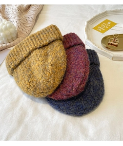 Close-up of mustard, burgundy and navy knit beanies arranged with decorative props