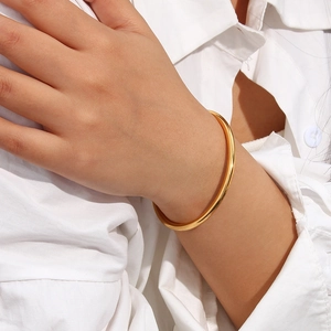Minimalist 18K gold plated stainless steel open bangle worn on a model's wrist