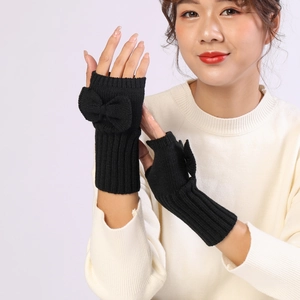 Close-up of black knit fingerless gloves with a decorative bow and textured wool-like finish