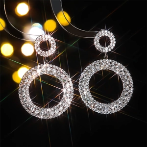 Boucles d'oreilles rondes argentées avec strass brillants sur fond noir élégant