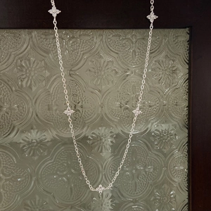 Macro detail of silver O-chain necklace with five clover charms set with clear zircons