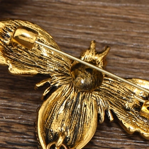 Macro shot of the vintage gold bee brooch back showing the secure safety pin and alloy texture