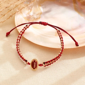 Detail van een handgeweven rugbyarmband in rood en beige koord op getextureerde stof