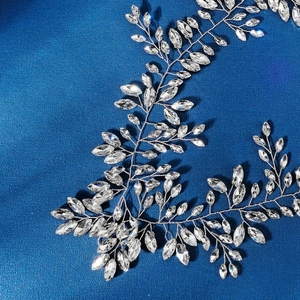 Detail of silver bridal headband with crystal leaves and rhinestone flowers on blue