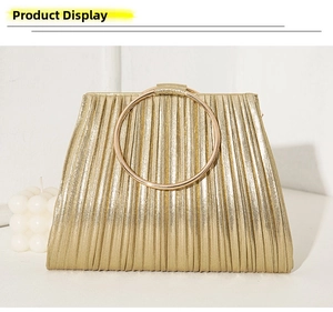 Detailed view of elegant pleated gold evening clutch with large metallic ring handle