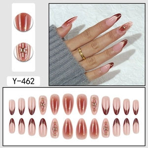 Almond-shaped press-on nails with red ombre, French tips, and 3D gold star accents