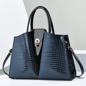 Detail of navy croc-embossed and black patent leather handbag with gold hardware
