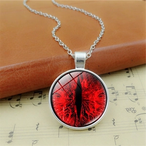 Detail of red dragon eye pendant necklace on vintage sheet music and leather book