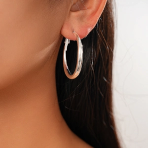 Close-up of a model wearing a silver geometric C-shaped earring with a polished finish