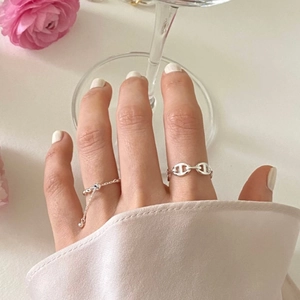 Detail of 925 sterling silver anchor link and chain rings on model hand with flowers