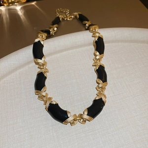 Détail du collier vintage en émail noir et doré avec des maillons à texture croisée