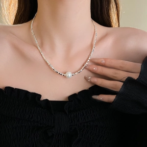 Detail of silver irregular beads necklace featuring a white pearl pendant on neck